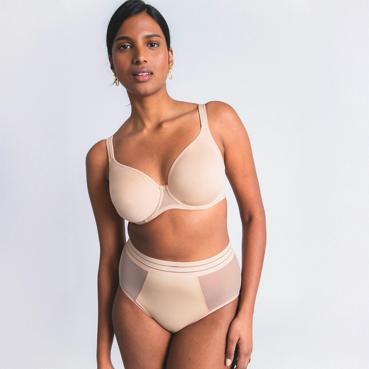 woman wearing a beige bra and panties set on a light gray background