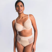 woman wearing a beige bra and panties set on a light gray background