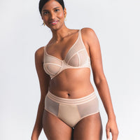 woman wearing a beige bra and panties set on a plain background