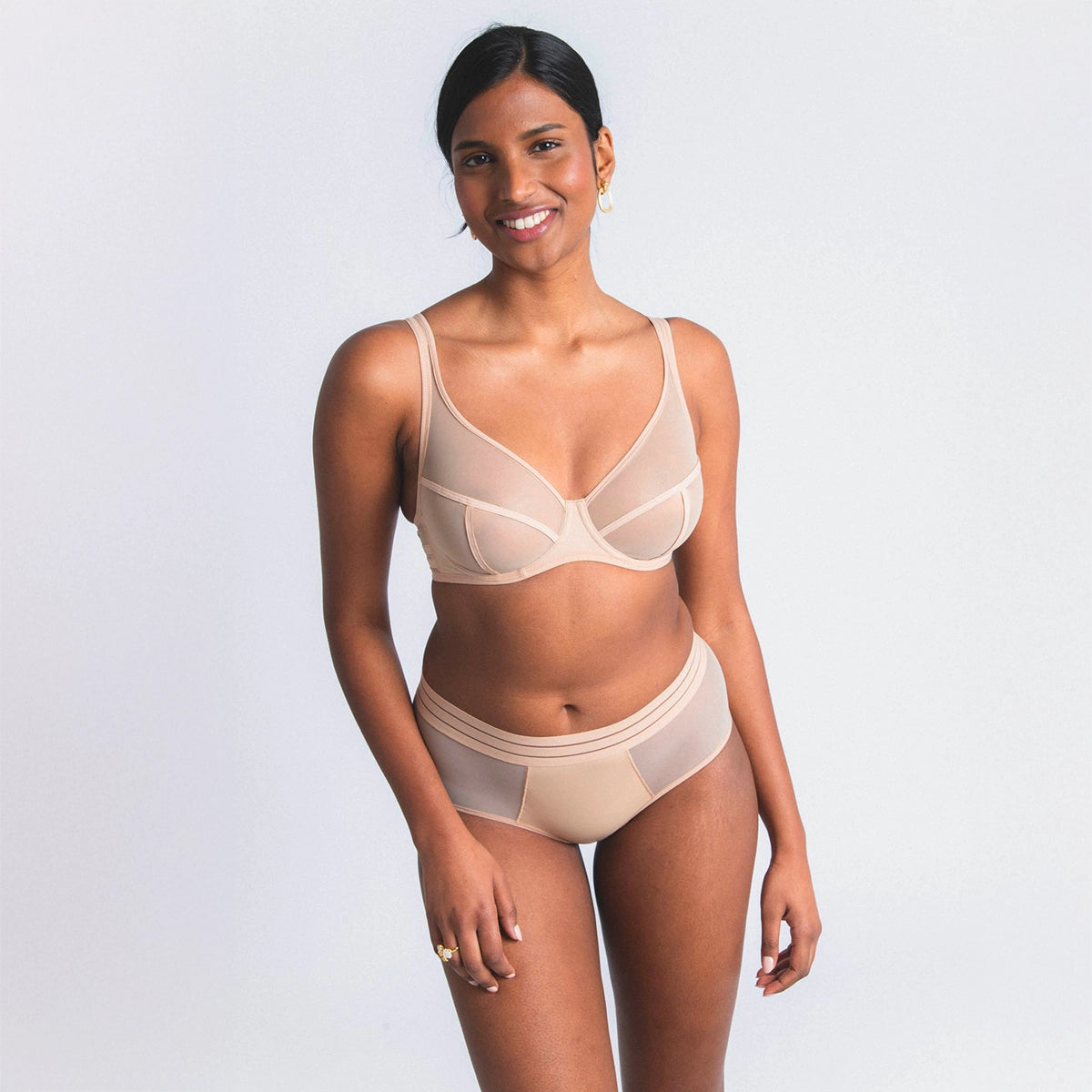 woman wearing a beige bra and underwear set on a light gray background