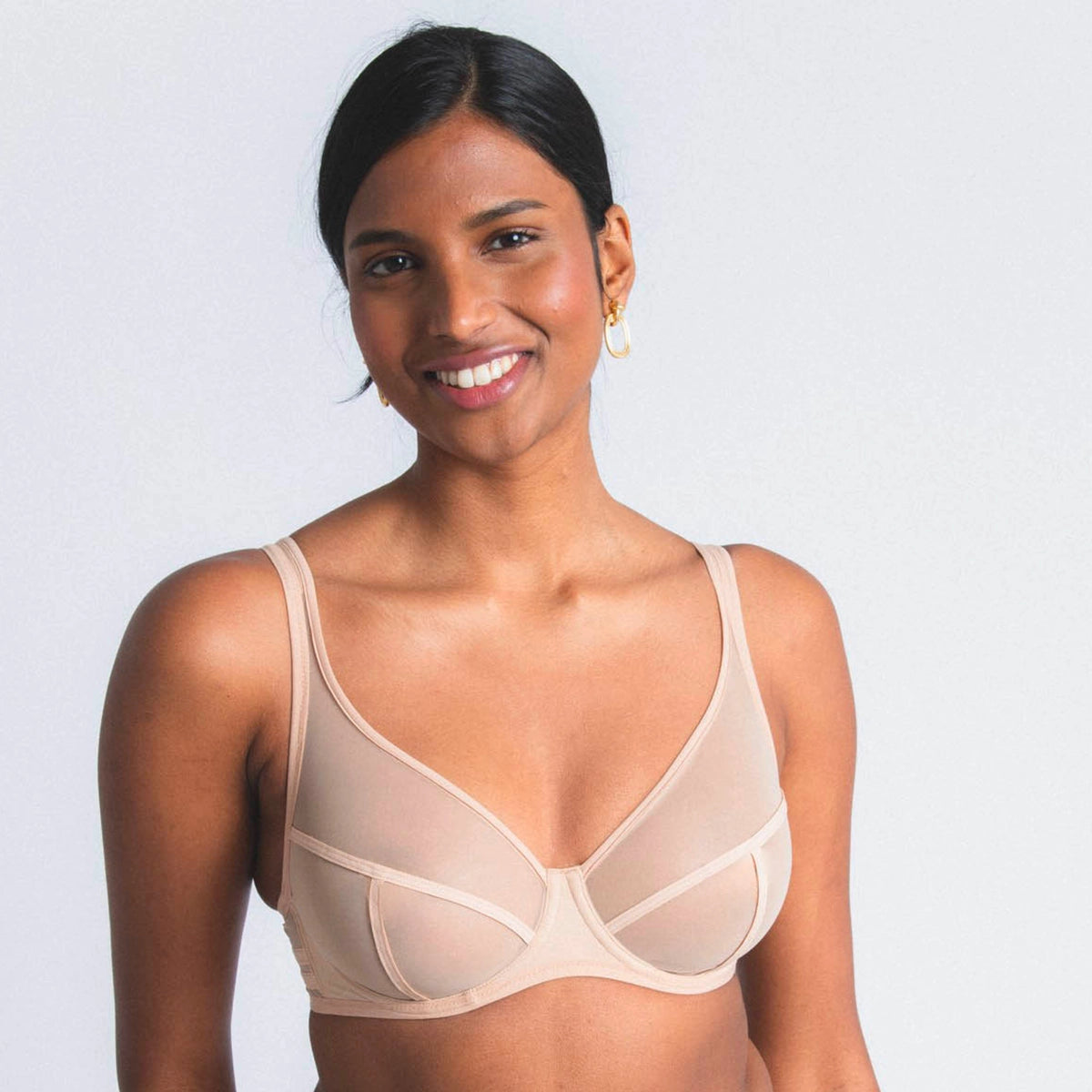 woman wearing a beige bra against a plain background