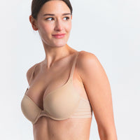 woman wearing a beige bra on a light gray background