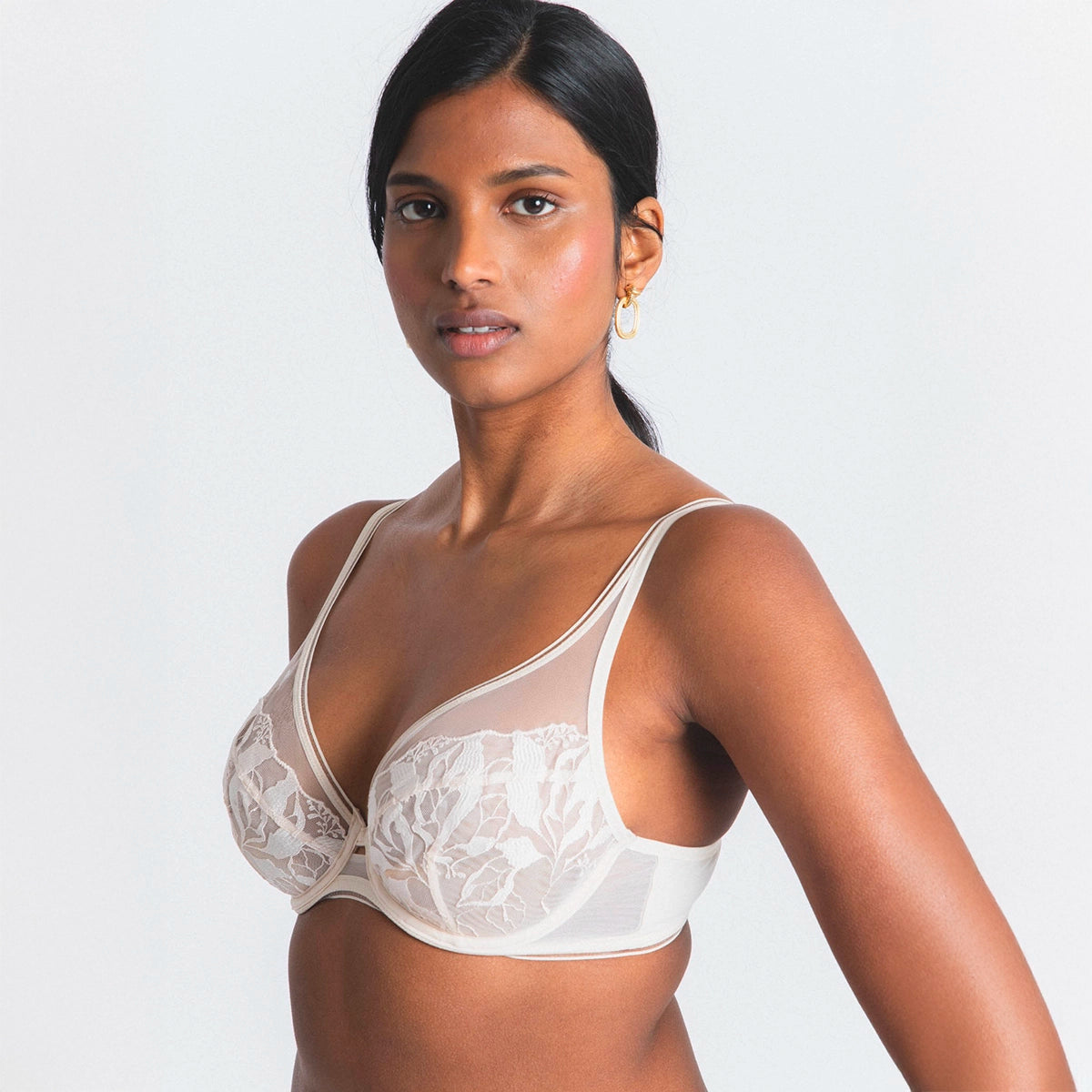 woman wearing a white lace bra against a plain background