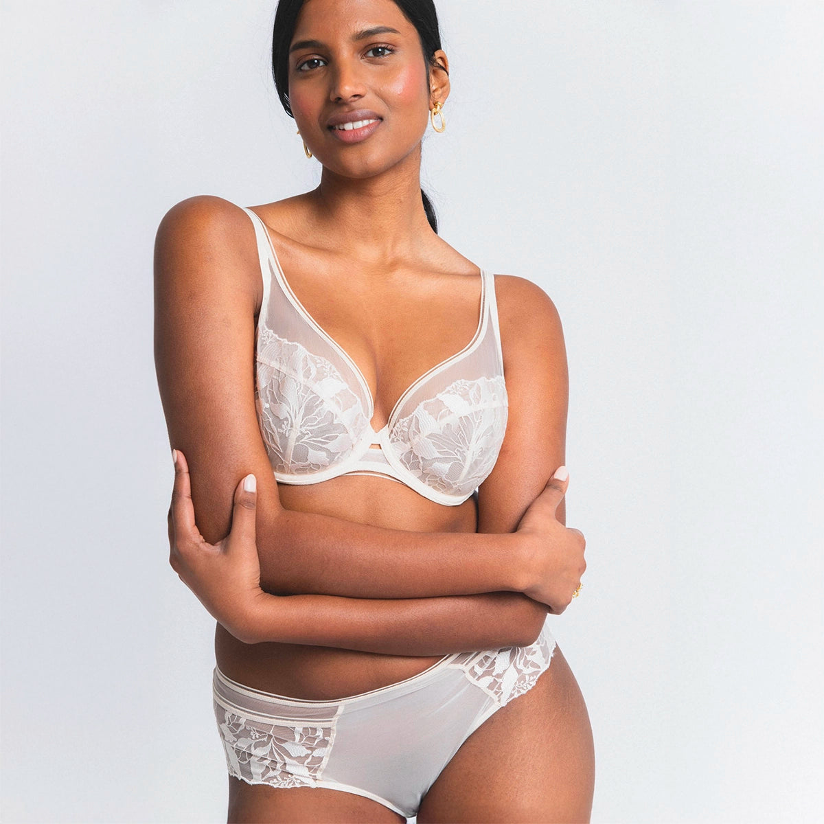 woman wearing a white lace bra and panties set on a plain background