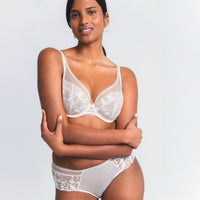 woman wearing a white lace bra and panties set on a plain background