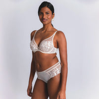 woman wearing a white lace bra and panties set on a plain background