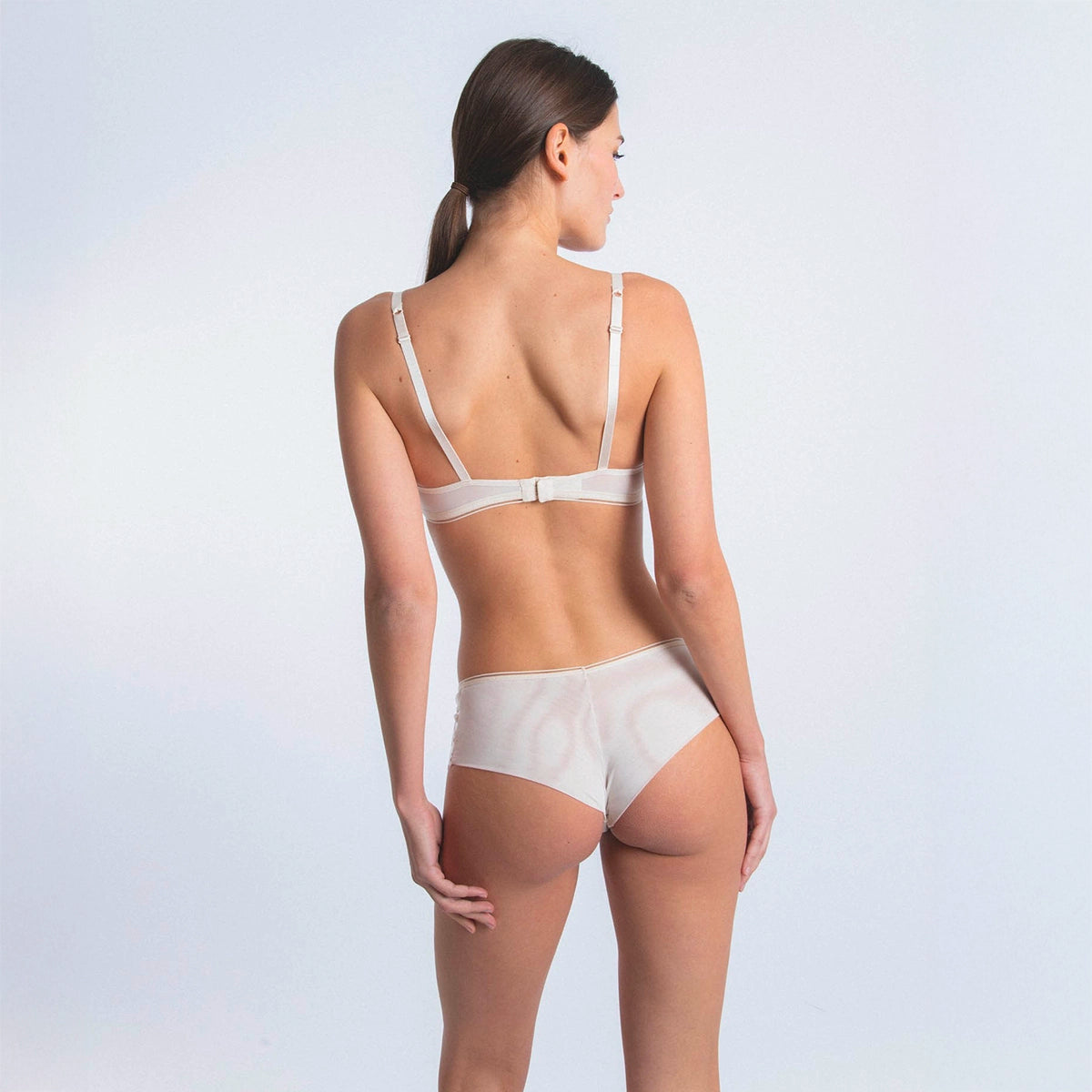 woman wearing a white bra and panties set on a light gray background