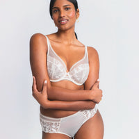 woman wearing a white lace bra and panties set on a plain background