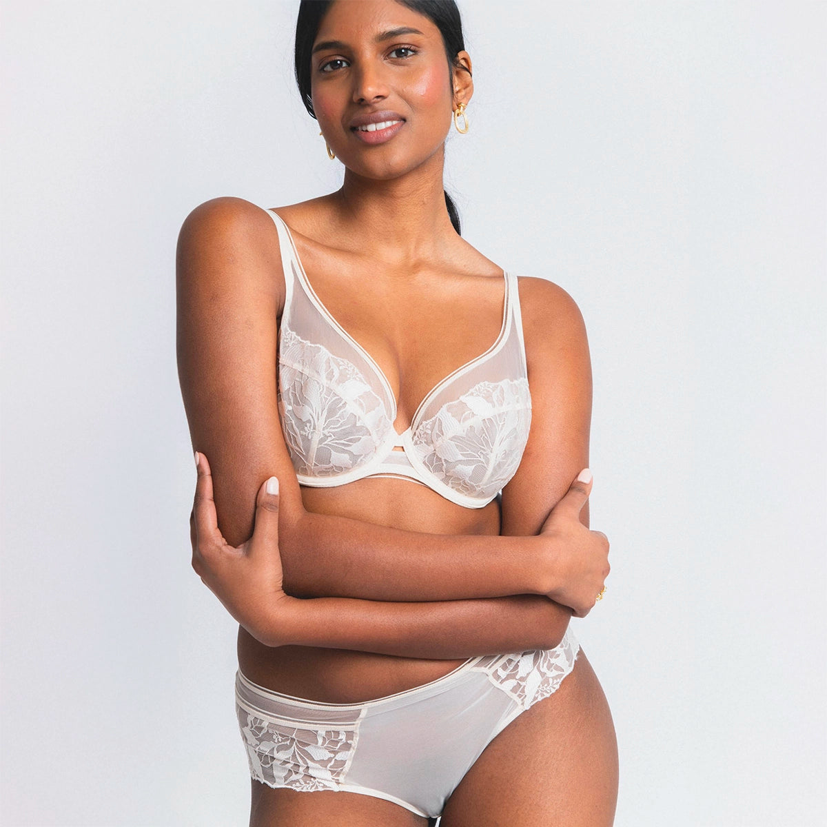 woman wearing a white lace bra and panties set on a plain background