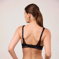 woman wearing a black bralette against a plain background
