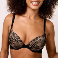 woman wearing a black lace bra against a neutral background