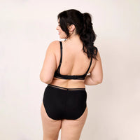 woman wearing a black swimsuit with lace details on a beige background