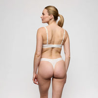 woman wearing a white bra and panties set on a plain background