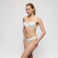 woman wearing a white bra and panties set against a plain background
