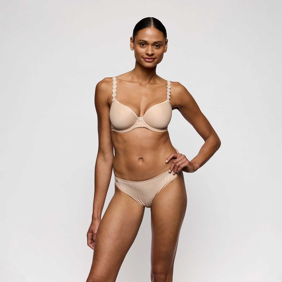 woman wearing a beige bra and panties set on a plain background