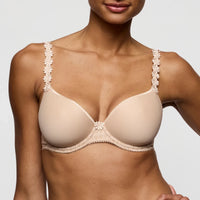 beige bra with floral straps worn by a model on a plain background