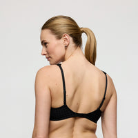 woman wearing a black bra against a plain background