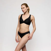 woman wearing a black lace lingerie set on a plain background