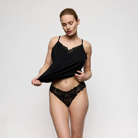 woman wearing black lace lingerie against a plain background
