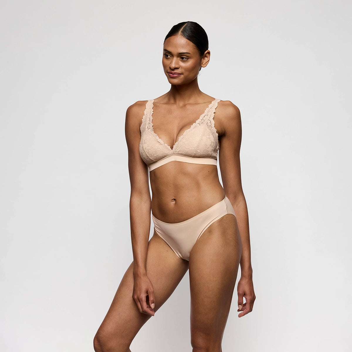 woman wearing a beige lingerie set on a plain background