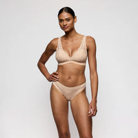 woman wearing a beige bra and panties set on a plain background
