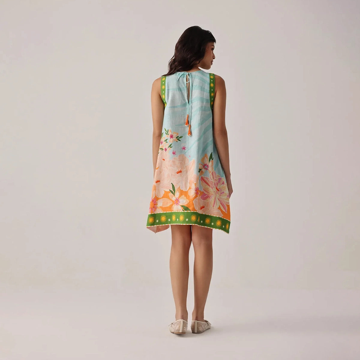 woman wearing a sleeveless floral dress on a plain background