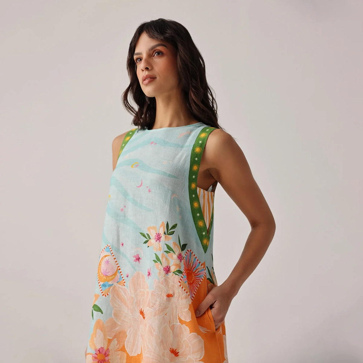 woman wearing a sleeveless dress with floral and abstract patterns on a plain background