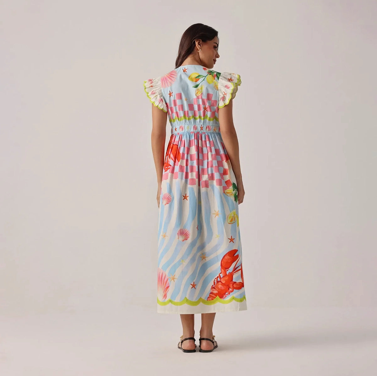 woman wearing a colourful dress with a pattern of flowers and stars on a plain background