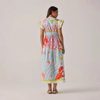 woman wearing a colourful dress with a pattern of flowers and stars on a plain background