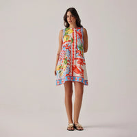 woman wearing a colourful sleeveless dress with a floral pattern on a plain background