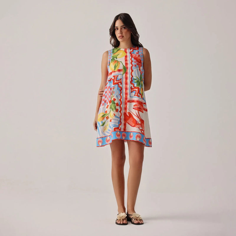 woman wearing a colourful sleeveless dress with a floral pattern on a plain background