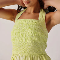 woman wearing a light green dress with smocked bodice on a plain background