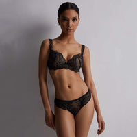 woman wearing a black lace lingerie set against a plain background