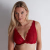 woman wearing a red bralette against a plain background
