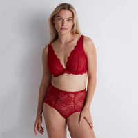 woman wearing a red lace lingerie set against a plain background