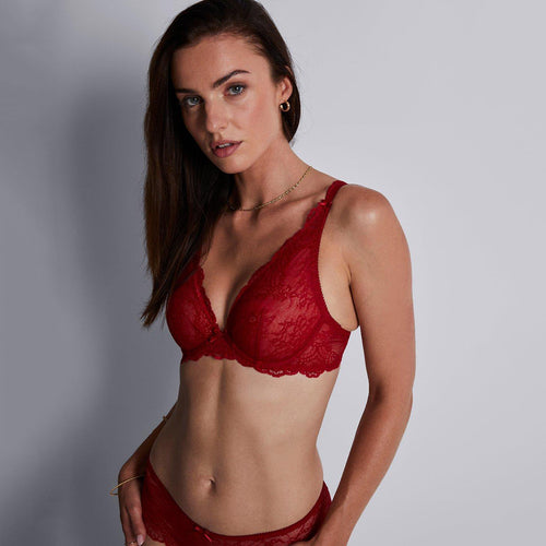 woman wearing a red lace bralette against a grey background
