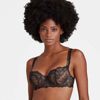 woman wearing a black lace bra against a plain background