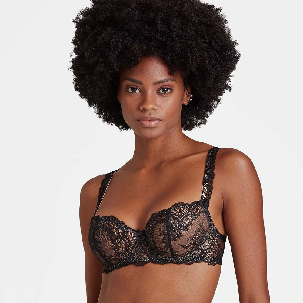 woman wearing a black lace bra against a plain background