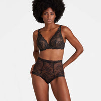 woman wearing a black lace lingerie set on a plain background