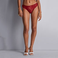 person wearing red lace lingerie against a gray background