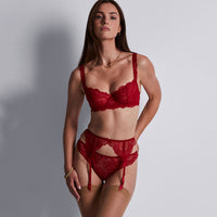 woman wearing a red lace lingerie set against a plain background