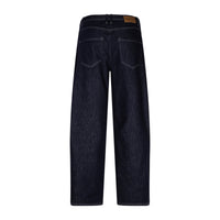 Back view of dark indigo denim jeans on a white background, showing the back pockets and a brown leather brand patch at the waistband.