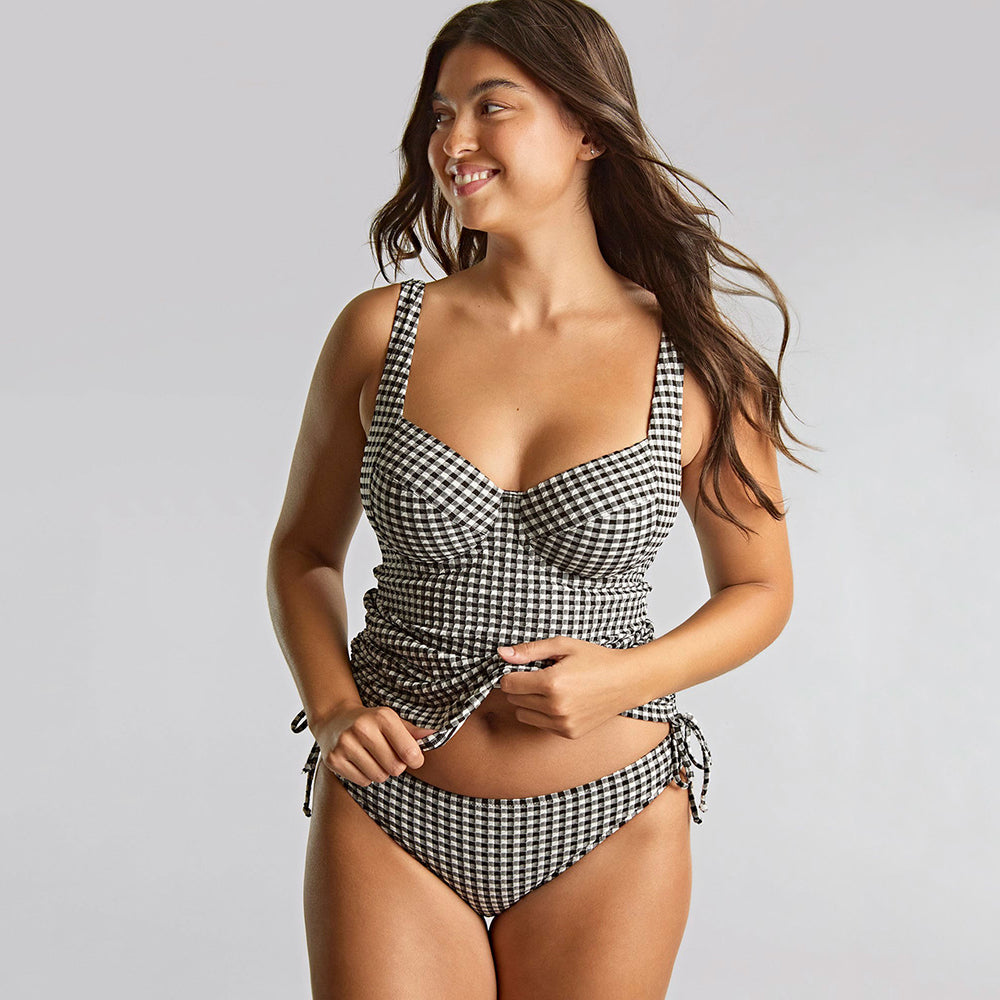 woman wearing a black and white checker tankini on a grey background