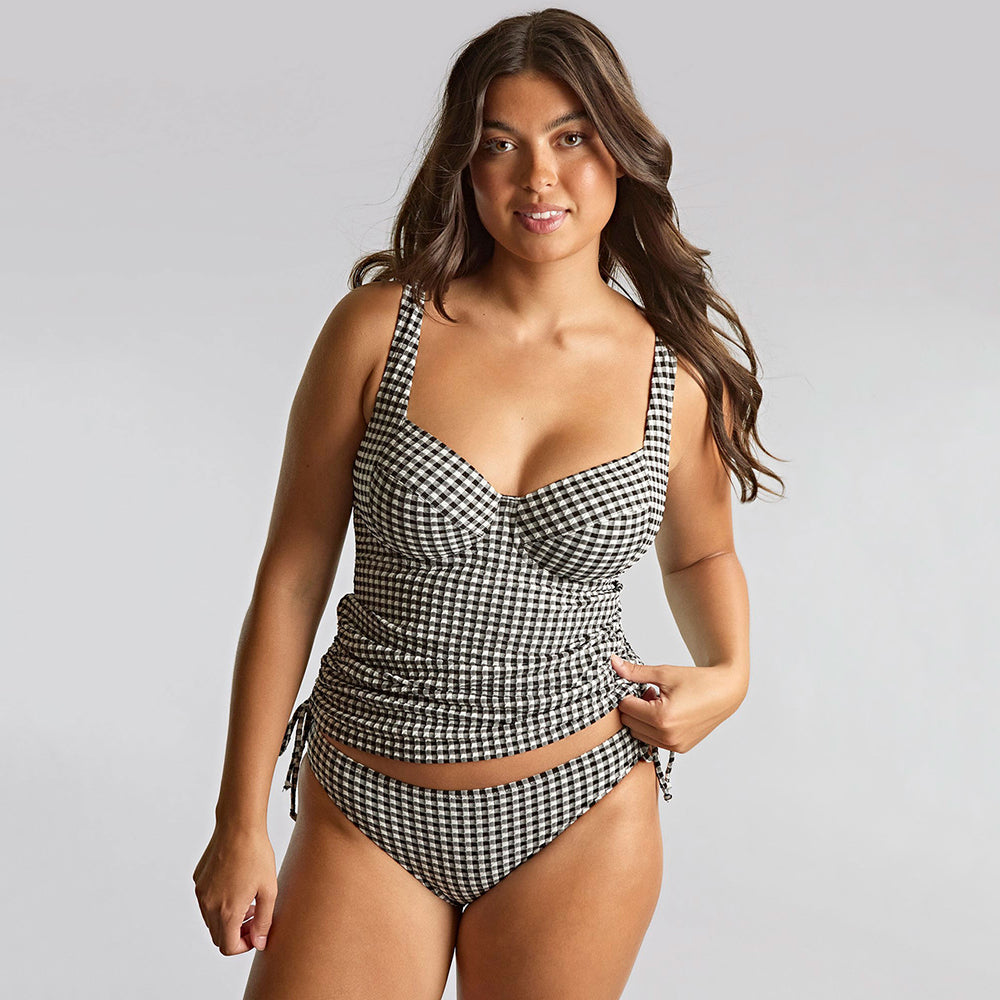 Woman wearing a black and white checker tankini on a grey background