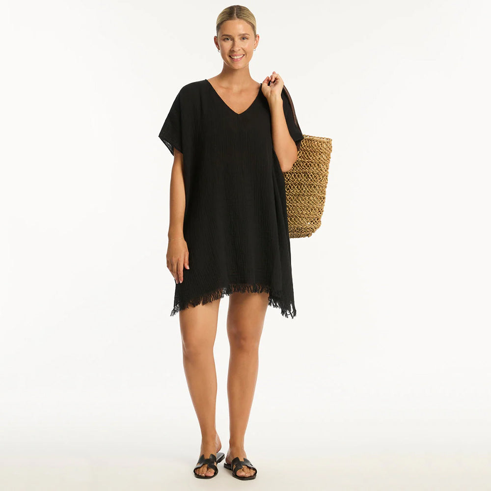 woman wearing a black dress holding a woven bag on a white background