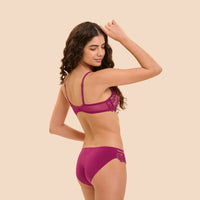 A woman modeling a matching magenta lace bra and underwear set, shown from the back against a solid beige background.