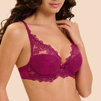 A close-up of a woman wearing a magenta lace bra against a solid beige background.