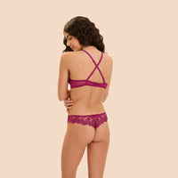 A woman shown from the back wearing a matching magenta lace lingerie set, consisting of a bra with crisscross straps and lace-trimmed panties, against a solid beige background.