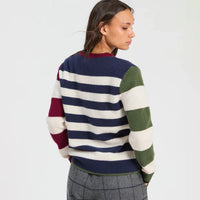 Back view of a cream and navy striped jumper with burgundy and green colour-block sleeves, a navy ribbed hem with green trim, paired with grey checked trousers.