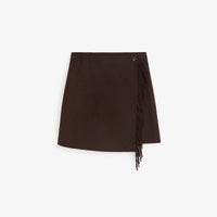 A dark brown asymmetrical wrap mini skirt with fringe detailing on the side, shown flat against a light gray background.